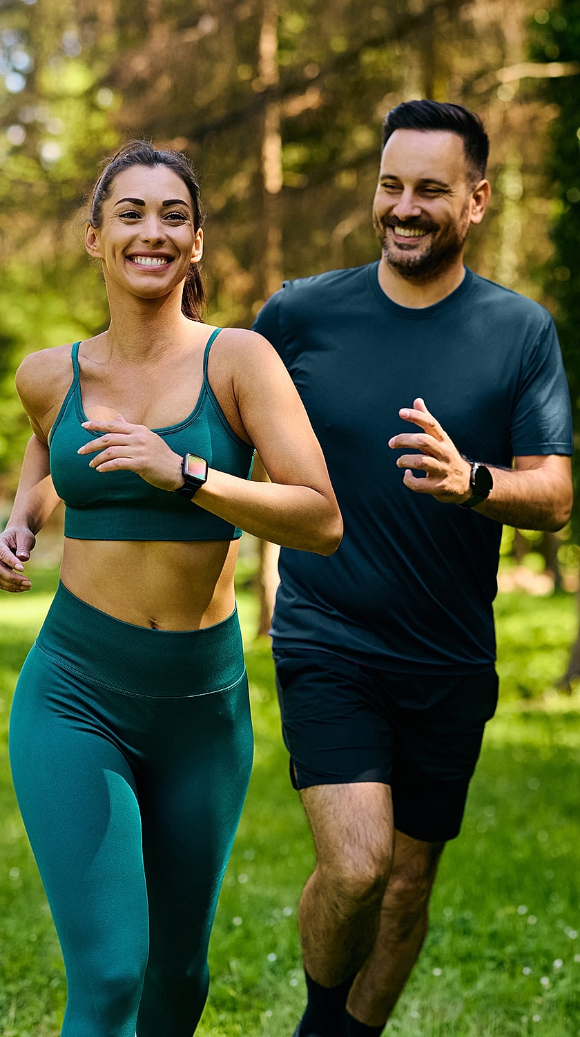 Couple jogging together in a green park.