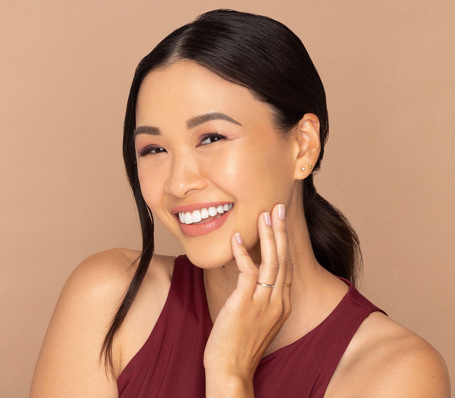 Smiling woman with natural makeup on neutral background.
