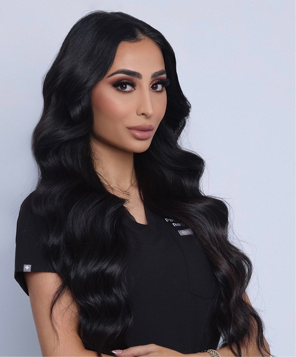 Woman with long, wavy black hair and makeup.