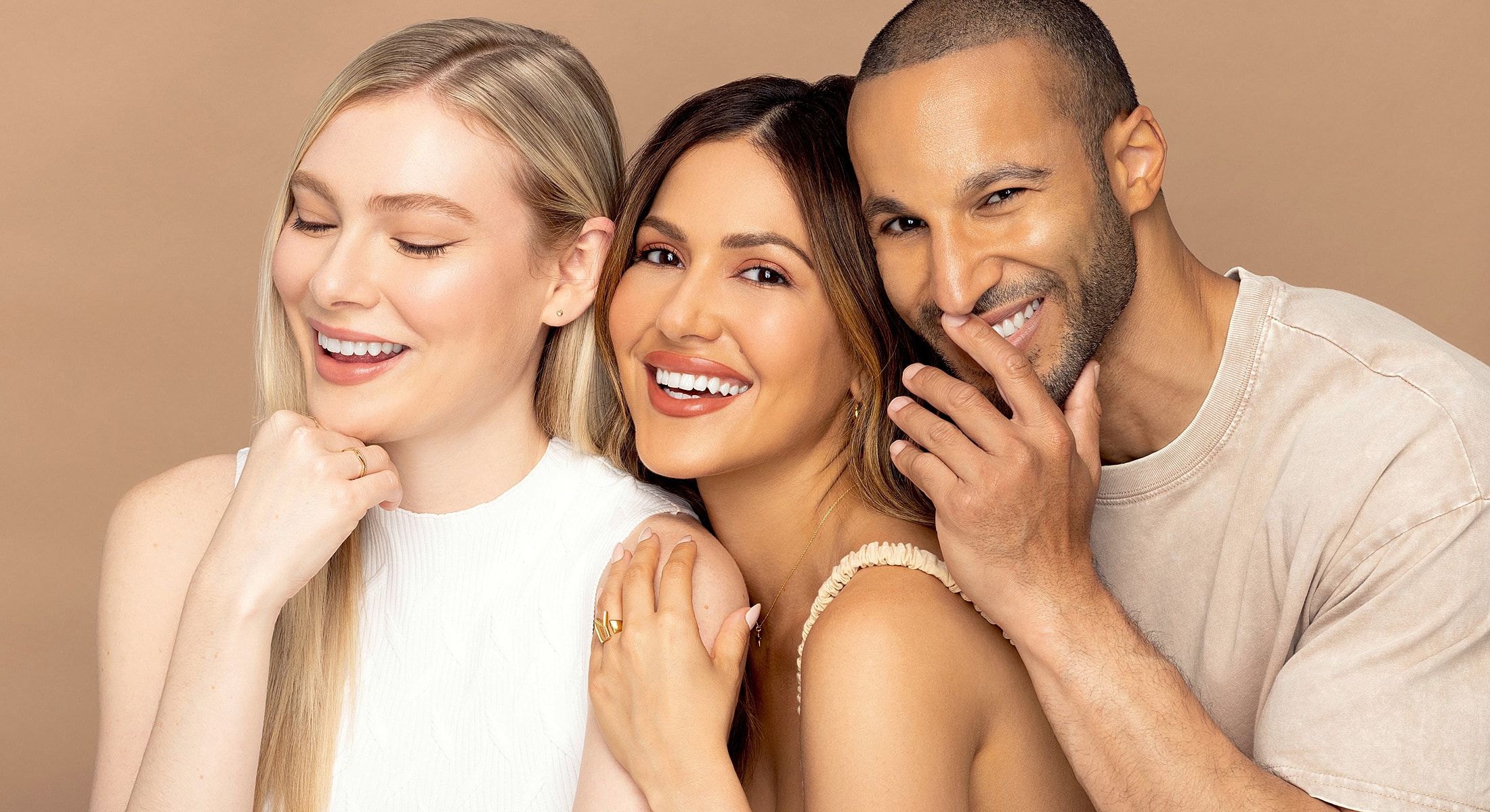 Three smiling individuals with joyful expressions.